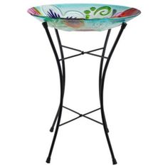 an iron stand with a colorful bowl on the top and metal legs, against a white background