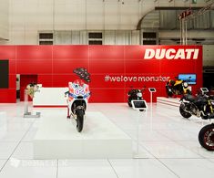 there are many motorcycles on display in the room with red walls and white flooring