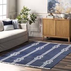 a living room with a white couch and blue rug on top of the wooden floor