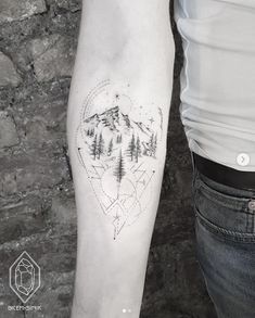 a person with a tattoo on their arm that has mountains and trees in the shape of a heart