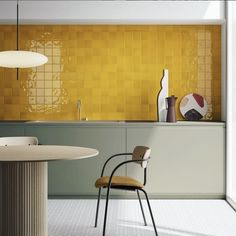 a modern kitchen with yellow tiles on the wall and white counter tops, along with a round dining table