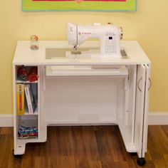 a sewing machine sitting on top of a white table next to a wall with a painting