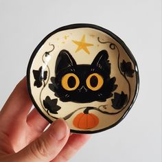 a hand holding a small black and white plate with a cat on it's face