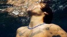 a man swimming in the water with tattoos on his chest