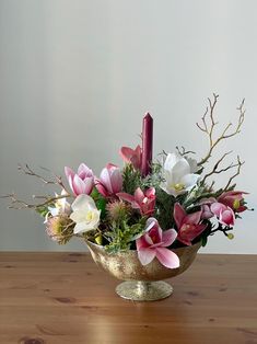 a vase filled with flowers on top of a wooden table next to a lit candle