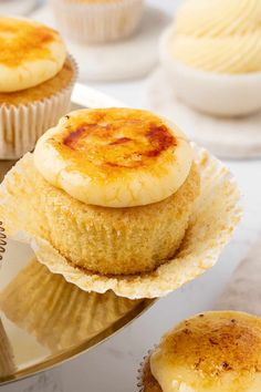 three cupcakes sitting on top of a cake plate next to other cupcakes