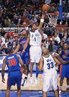 a group of men playing basketball in front of an arena full of people and fans