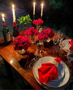 the table is set with red roses and candles