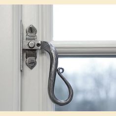 a metal hook on the side of a white door with a window in the background