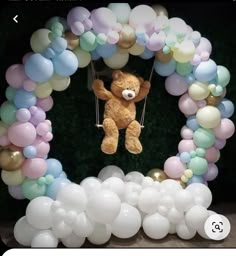 there is a teddy bear hanging from a balloon arch with balloons in the shape of a circle