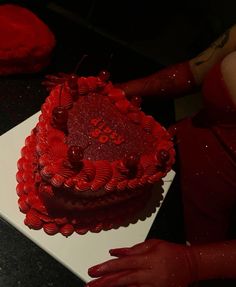 a heart shaped cake sitting on top of a white plate next to a woman's hand