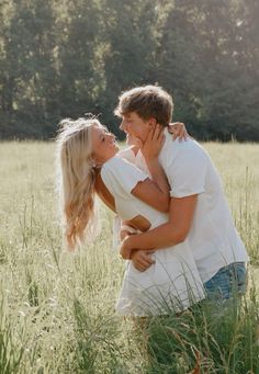 a man and woman are hugging in the tall grass