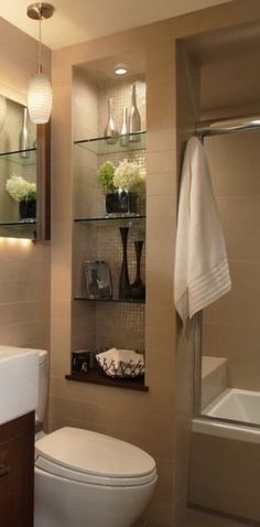 a white toilet sitting next to a bath tub in a bathroom under two hanging lights