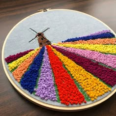 a close up of a cross stitch pattern on a wooden table with a circular frame