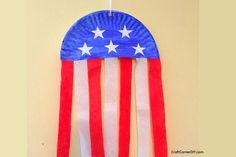 a paper plate with an american flag design on it hanging from a hook in a wall