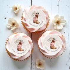 three cupcakes decorated with pink frosting and flowers