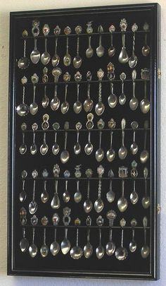 a wall mounted display with spoons and other silverware on black board, hanging from the wall