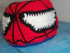 a crocheted spiderman hat sitting on top of a blue table