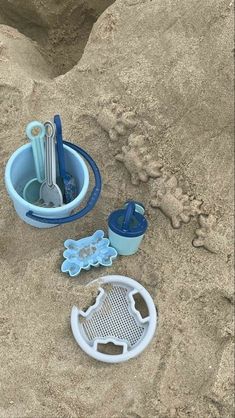 an assortment of beach items including toothbrushes and cups in the sand at the beach