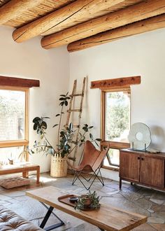 a living room filled with furniture and lots of wooden beams on the ceiling, along with two windows