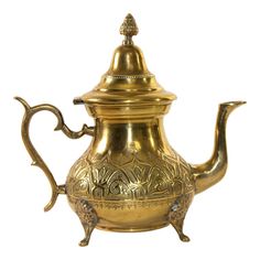 a brass teapot with ornate designs on the top and bottom, is shown against a white background