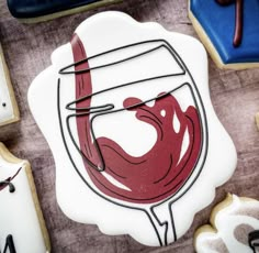 a cookie with a glass of wine on it next to cookies and icing cutters