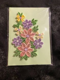 a card with flowers made out of rolled paper