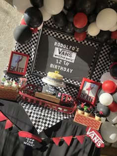 a birthday party with black and white balloons, red and gray decorations and pictures on the wall