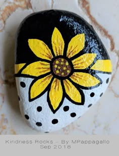 a painted rock with a yellow flower on it