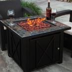 a fire pit sitting on top of a patio next to a table with wine glasses