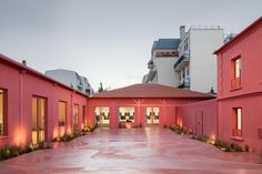 an empty courtyard with red walls and plants on the ground in front of buildings at dusk