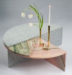 a table with a vase and two candles on it next to a marble slab that has flowers in it