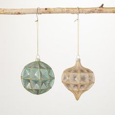 two ornaments hanging from a tree branch on a white background, one is green and the other is blue