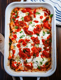 a casserole dish with tomatoes, cheese and basil on top is ready to be eaten