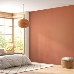 a bedroom with an orange wall and white bedding in the foreground is a basket on the floor