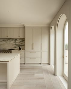 a large kitchen with white cabinets and marble counter tops, along with arched doorways