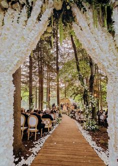 an outdoor wedding ceremony with white flowers and greenery on the aisle leading into the forest