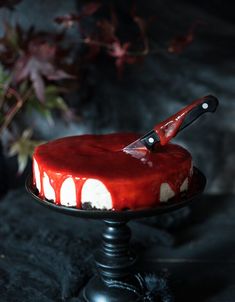 a red and white cake sitting on top of a black plate with a knife stuck in it