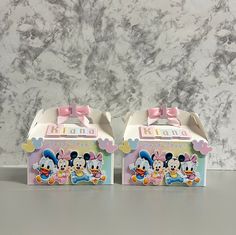 two boxes with minnie mouse designs on them sitting on a table next to a marble wall