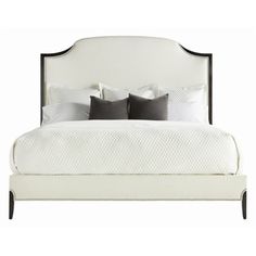 a white bed with four pillows and two night stands on top of the headboard