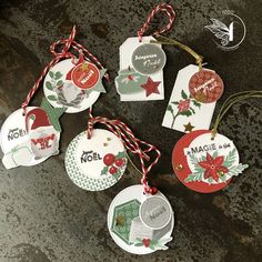 some tags are hanging on a table with red and green ribbons around them that say merry