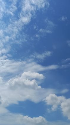 an airplane is flying high in the sky with some clouds above it and another plane on the ground