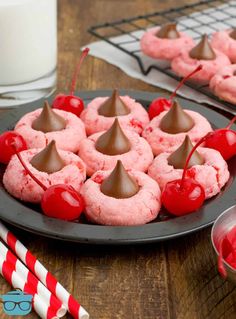 a plate full of pink cookies with chocolate on top and cherries in the middle