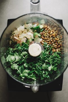 a food processor filled with greens and nuts