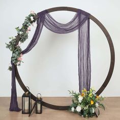 an arch decorated with flowers and greenery sits next to a lantern on the floor