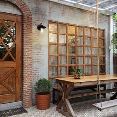 a wooden bench sitting in front of a brick building next to a tree and potted plants