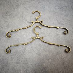 three brass coat hangers on a gray background