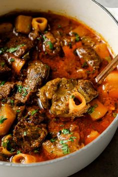 a pot filled with meat and pasta in tomato sauce, garnished with parsley