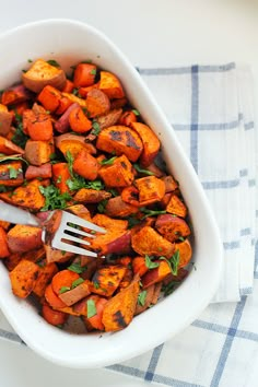 a white bowl filled with cooked carrots on top of a blue and white towel