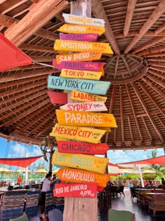 a pole with many signs on it in the middle of a covered outdoor dining area